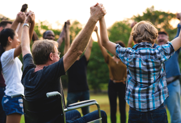 Celebrating brain injury awareness, holding hands in a victory circle in the park